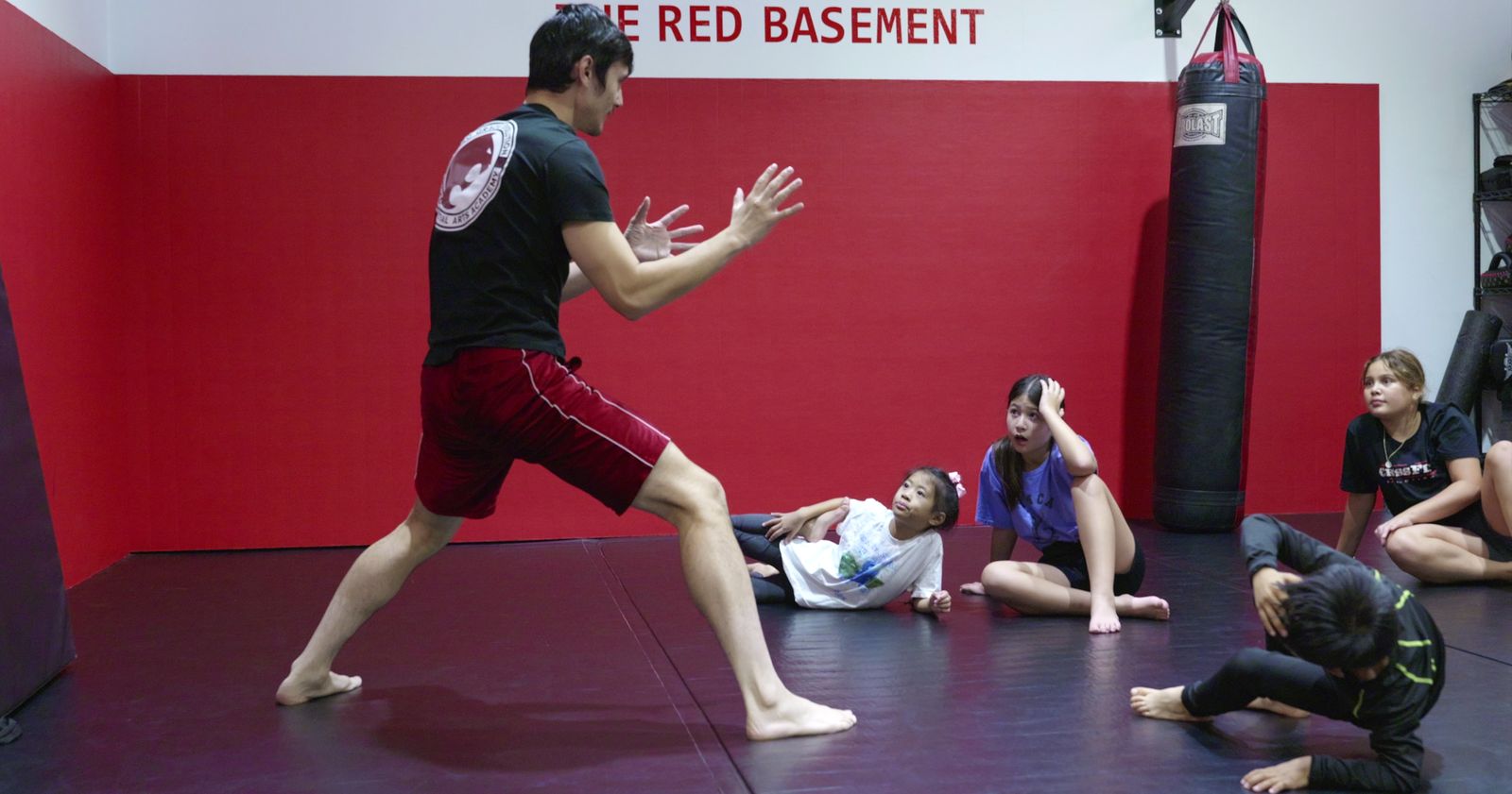 Instructor demonstrating a technique to seated kids in the Kids Jiu Jitsu class at Renzo Gracie Evolution